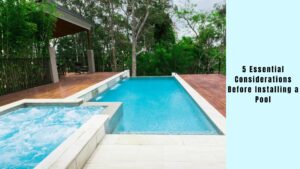 A pool with a spa and a deck in the background.